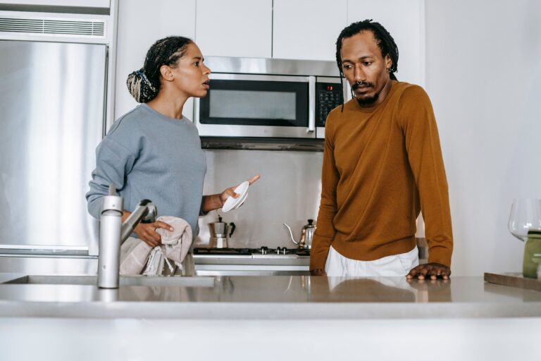African American guy and lady in casual clothes standing and arguing in kitchen in daytime